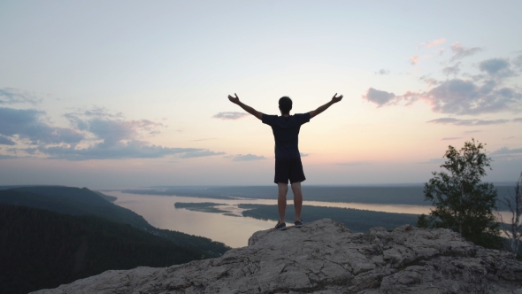 Silhouette Of a Businessman With a Laptop In Hand Is On Top Of a Mountain In The Sky With Clouds.