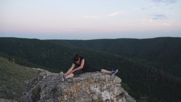 Young Woman Doing Exercises For Stretching On Top Of a Mountain