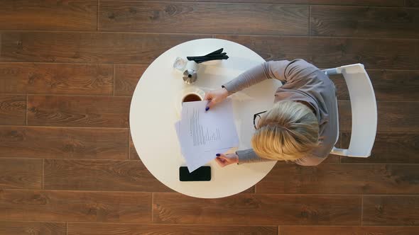 Smiling Woman Holding Document in Cafe