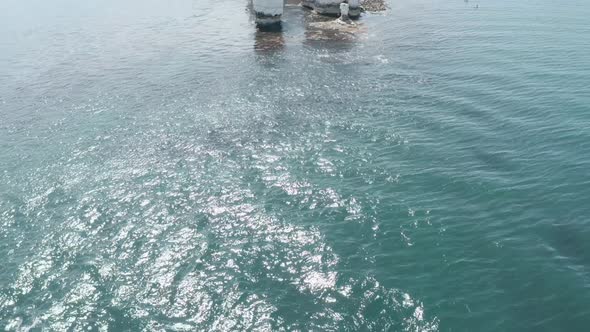 Pan up reveal drone shot of Old Harry rocks from the sea