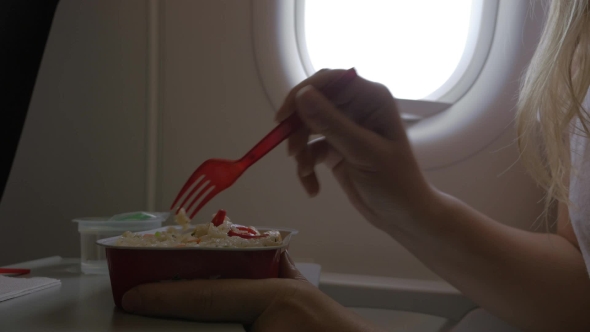 Clip Of Woman Eating Airplane Dinner Rise With Vegetables By Plastic Fork Against Window