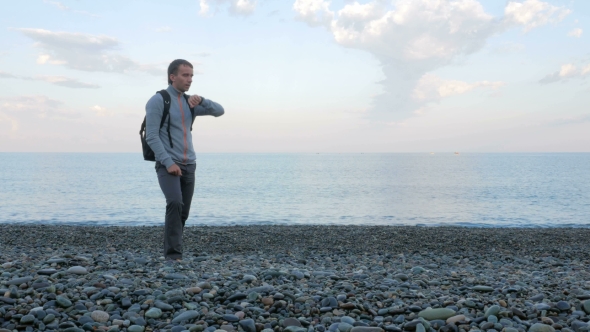 A Man Walks Along The Beach And Check The Messages On The Smart Watch Near The Ocean. He Is