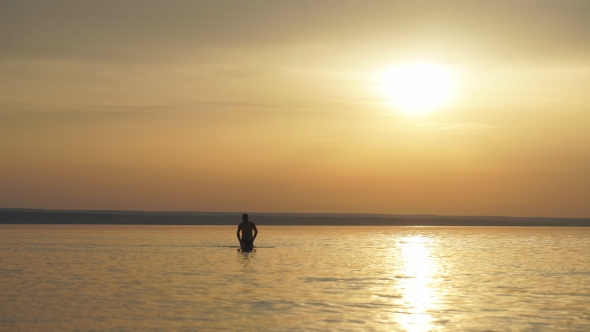 Man In Water On a Sea In a Sunrise