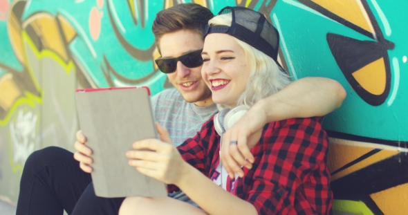 Laughing Young Hipster Couple Checking a Tablet