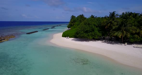 Beautiful fly over clean view of a white sand paradise beach and blue water background 