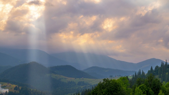 Sun Rays Pass through the Clouds Over the Mountains at Sunset.