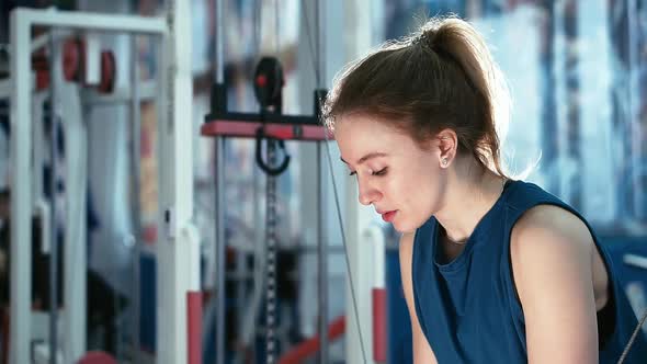 Side View, Muscular Athlete Girl Engaged in Lifting Weights on the Simulator