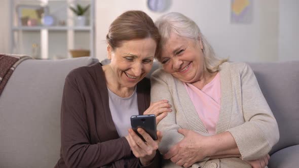 Cheerful Old Women Watching Photos on Smartphone and Laughing, Good Memories