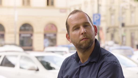 A Caucasian Man Thinks About Something with a Smile in an Urban Area  Closeup