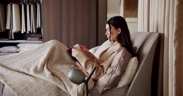 Woman Relaxing in Bed and Reading a Book in the Bedroom in the Modern House