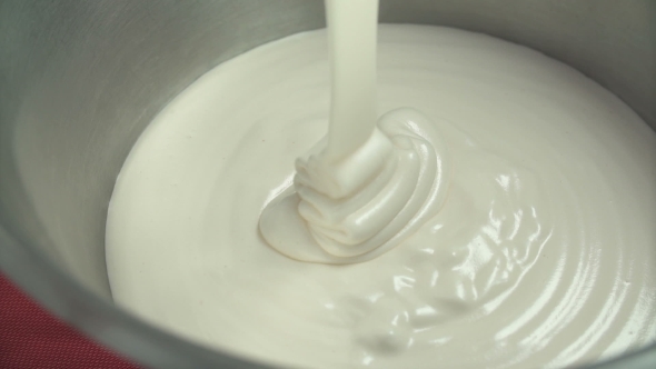 Pastry Cook Pours Thick White Cream In a Bowl