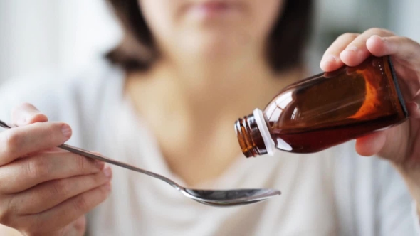 Woman Pouring Medication To Spoon