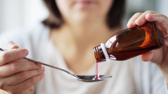 Woman Pouring Medication To Spoon