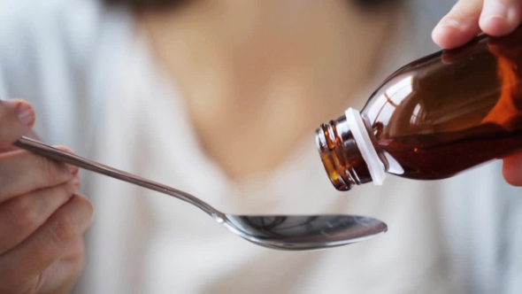 Woman Pouring Medication To Spoon