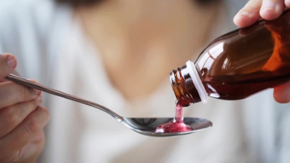 Woman Pouring Medication To Spoon