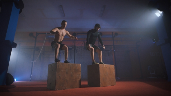 Two Men Doing a Box Jump At The Gym.