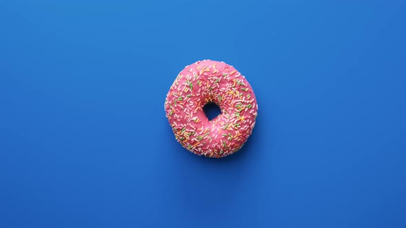 Slowly Rotating of Sweet Bright Doughnut with Colorful Icing Chocolate Isolated on Blue