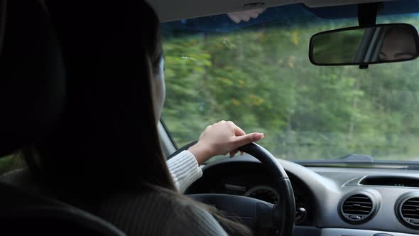 Woman Driving a Car Through the Woods Back View