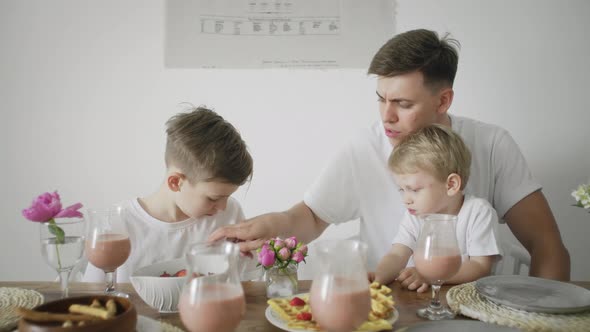 Handsome Father and Two His Sons Having Breakfast at the Morning