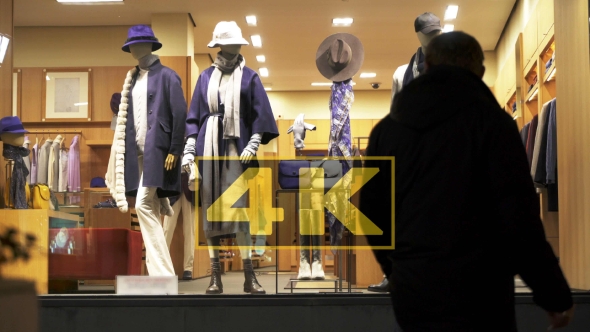 Silhouettes Of Pedestrians In Front Of Mannequins In Window Of Shop