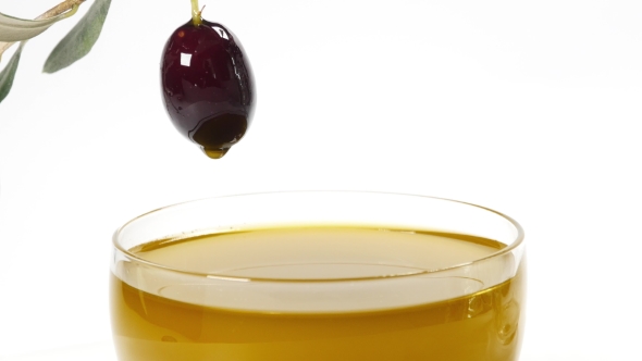 A Drop Of Olive Oil Falling From One Black Olive