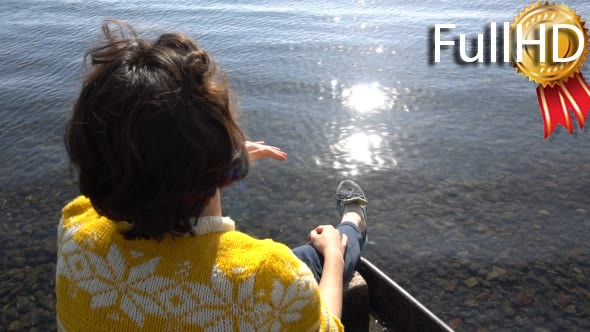 Young Brunette Girl is Sitting in Boat on Lake.