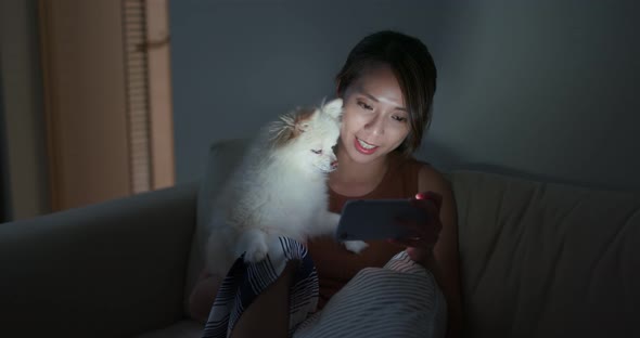 Woman look at cellphone with Pomeranian dog at home