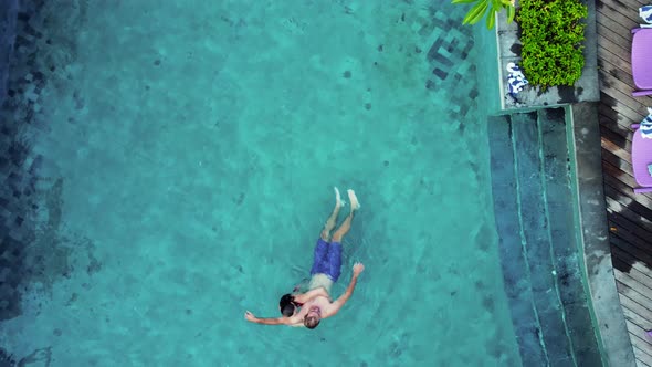 Young Couple Play on Hotel Pool with Blue Water