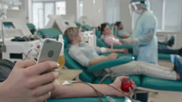 Young Man Using gadget while Blood Draw Procedure