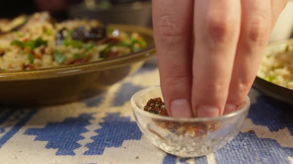 Sprinkling Spices on Bulgur with Eggplant Closeup Adding Pepper