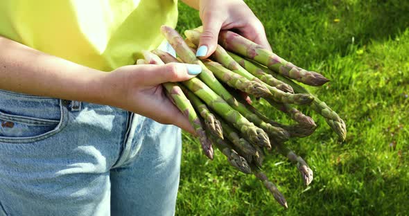 Woman holding a bunch of green asparagus in his hands outdoor