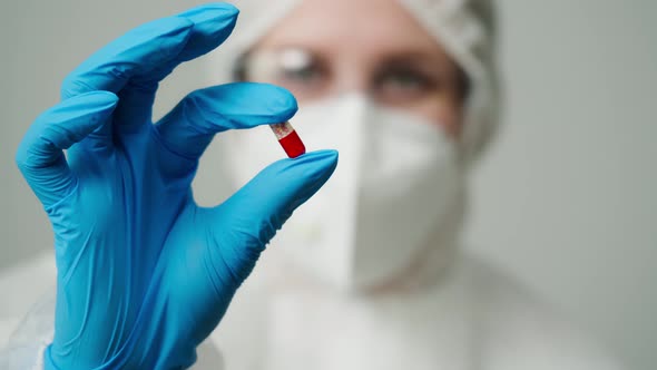 Closeup of Doctor in Protective Medical Uniform Nurse Wearing Face Mask Glasses and Blue Gloves