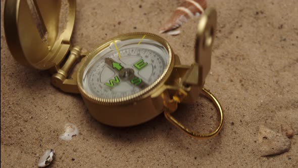 Throwing Gold Compass on Sand Background Closeup Golden Compass