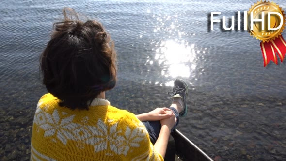 Young Brunette Girl is Sitting in Boat on Lake.