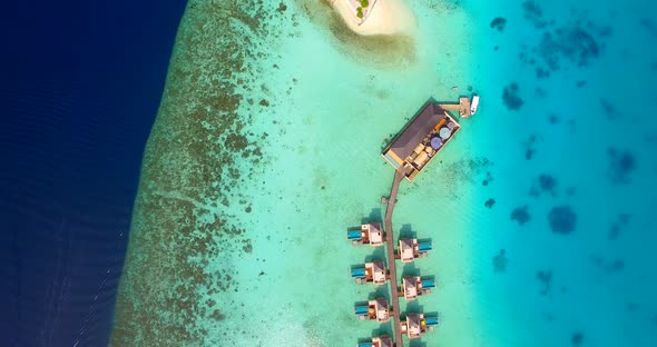 Aerial drone view of scenic tropical island and resort hotel with overwater bungalows in Maldives.