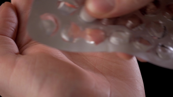 Man's Hand Taking Out Pills From Blister Pack Isolated On Black