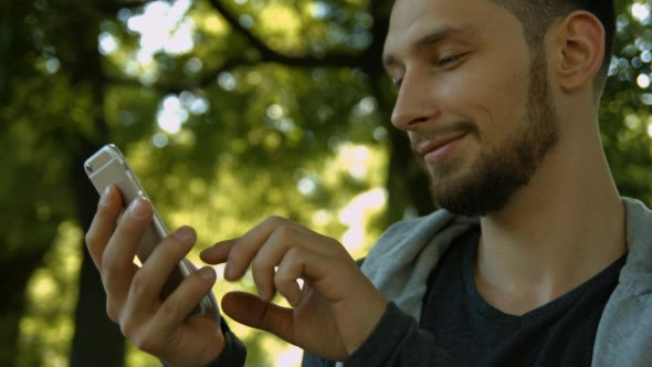 Young Man Using a Phone in Park