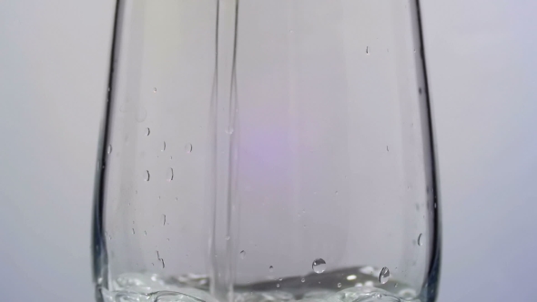 Water Is Poured Into a Transparent Glass On a White Background.