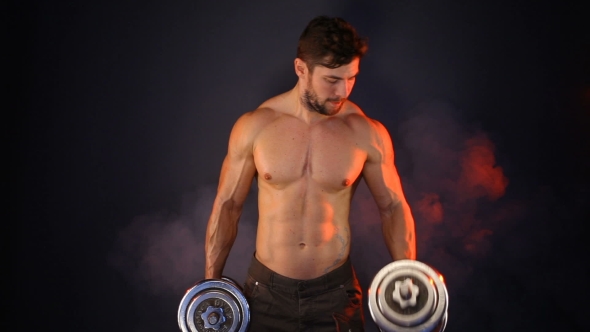 Strong Sportsman Lifting Heavy Dumbbells In Smoke