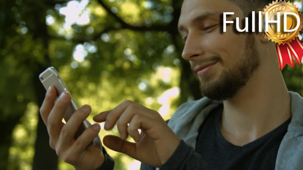 Young Man Using a Phone in Park