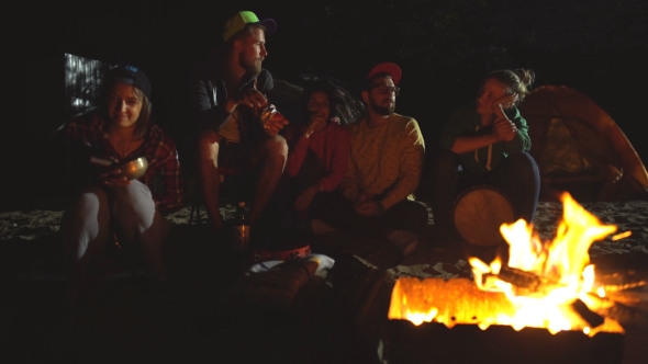 Group Of Backpackers Relaxing Near Campfire After a Hard Day