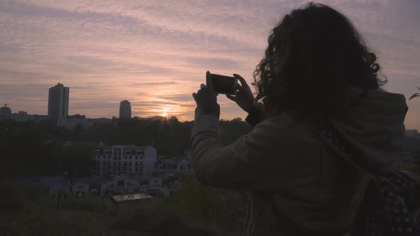 Happy Female Student Shooting Video of Beautiful Sunset in Big City on Gadget