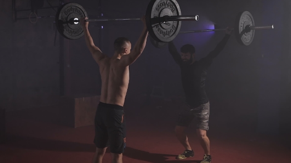 Two Strong Men Doing Weightlifting With Barbell At The Gym Simultaniously.