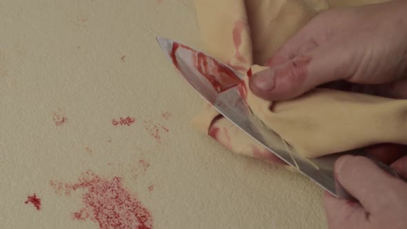 Bloody hand of criminal murderer wiping blood of a knife after stabbing