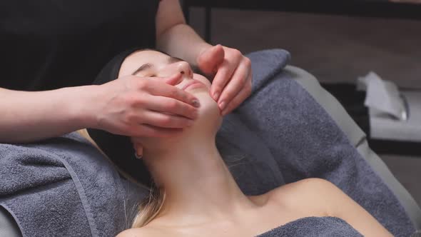 Young Woman Receives Facial Muscle Relaxation and Buccal Massage in a Luxury Beauty Salon