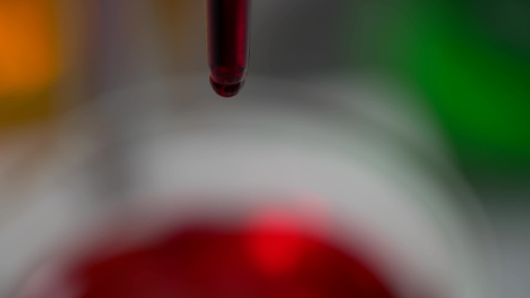 Red Liquid Dripping Into The Flask In a Laboratory