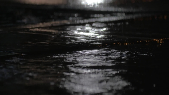 Rain Puddles And Falling Drops Against Car City Lights