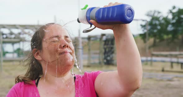 Caucasian woman pouring water on her face at bootcamp