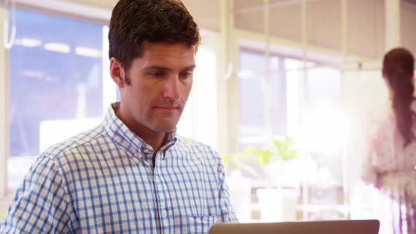 Male business executive having coffee while using laptop