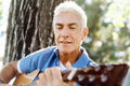 Senior man plying guitar outdoors - PhotoDune Item for Sale